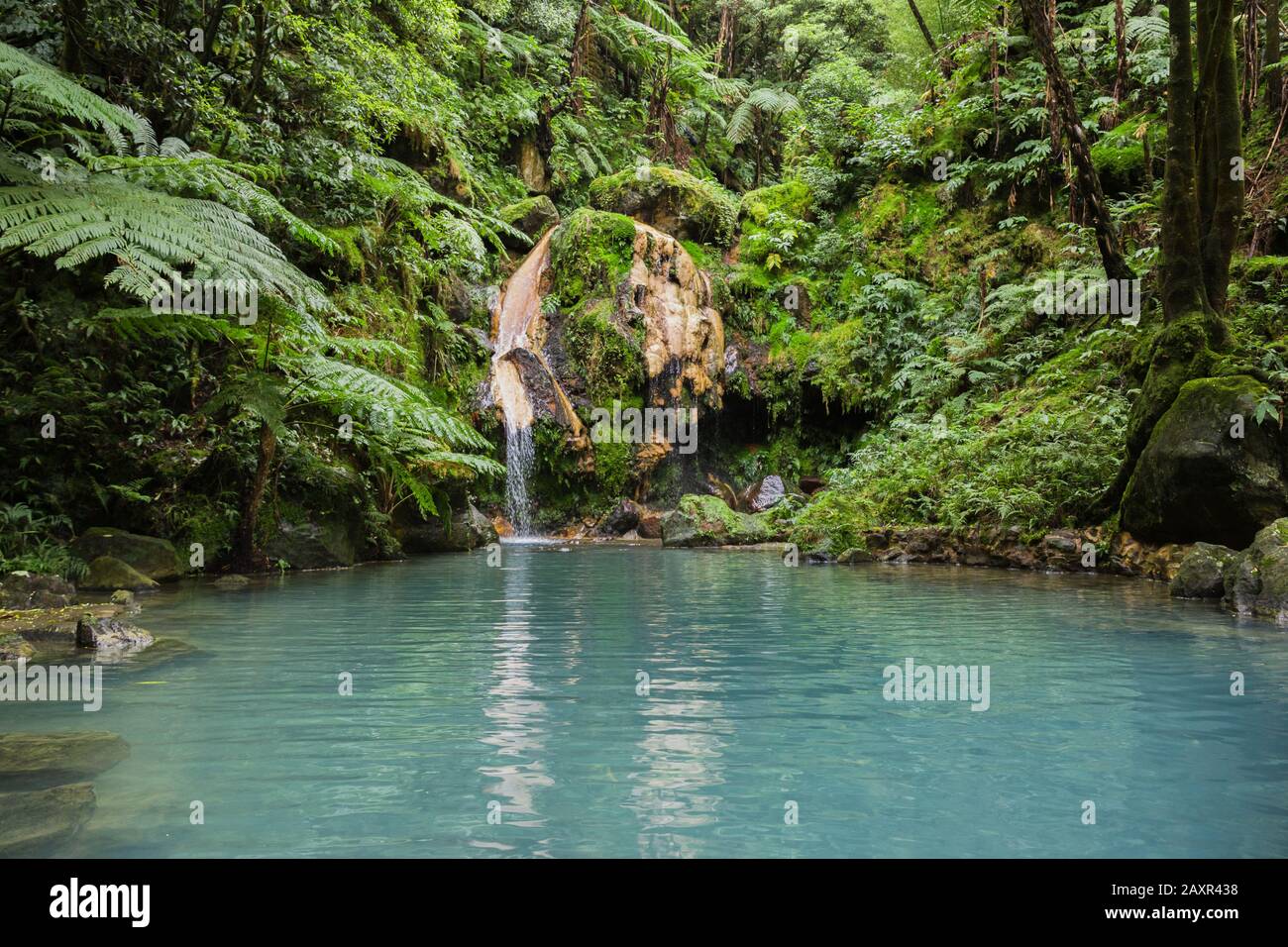 Blue lagoon of natural hot spring at 'Caldeira Velha' where people swim in warm water in Sao Miguel island, Azores, Portugal Stock Photo