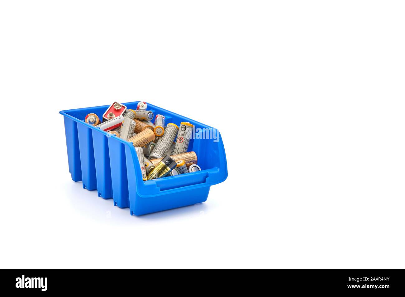 Many depleted batteries in a blue recycle bin photographed on a white background. Stock Photo