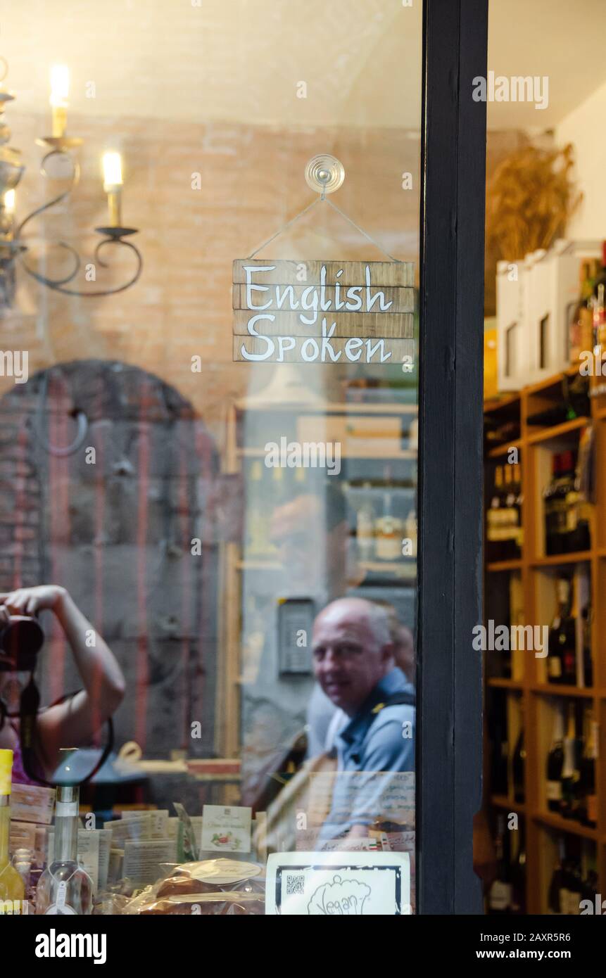 An 'English Spoken' hangs in the window of a book store in Lucca, Italy. Stock Photo