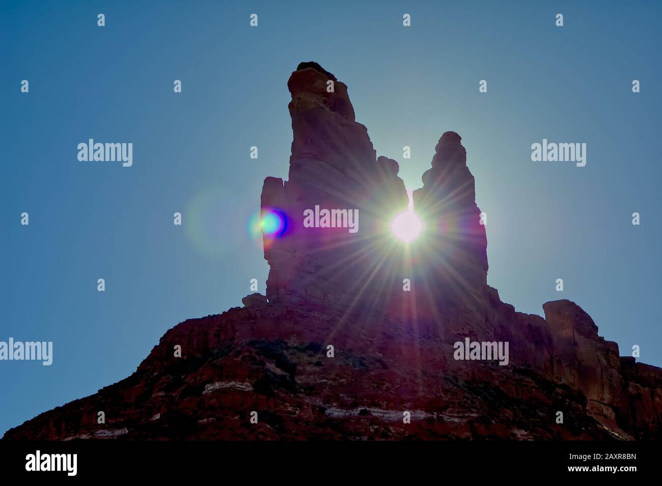 The sun setting behind a rock formation in Valley of the Gods known as ...