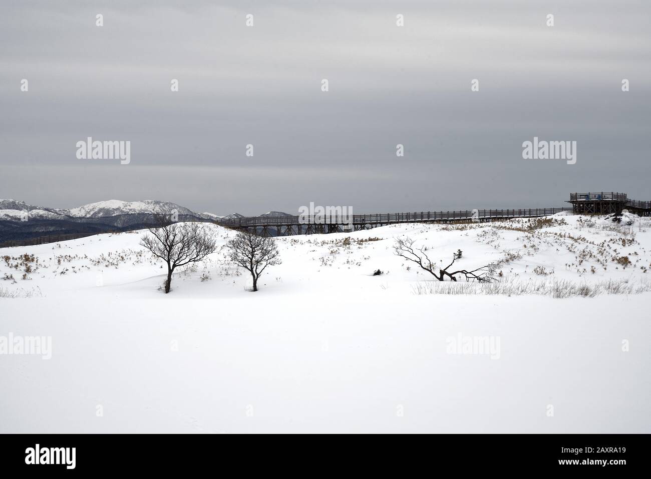 Hiking through snow covered Shiretoko Five Lakes in winter with Shiretoko mountain range and observation deck in the background, Hokkaido, Japan Stock Photo
