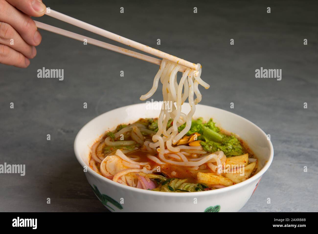 hand with chopstick and laksa curry noodles Stock Photo