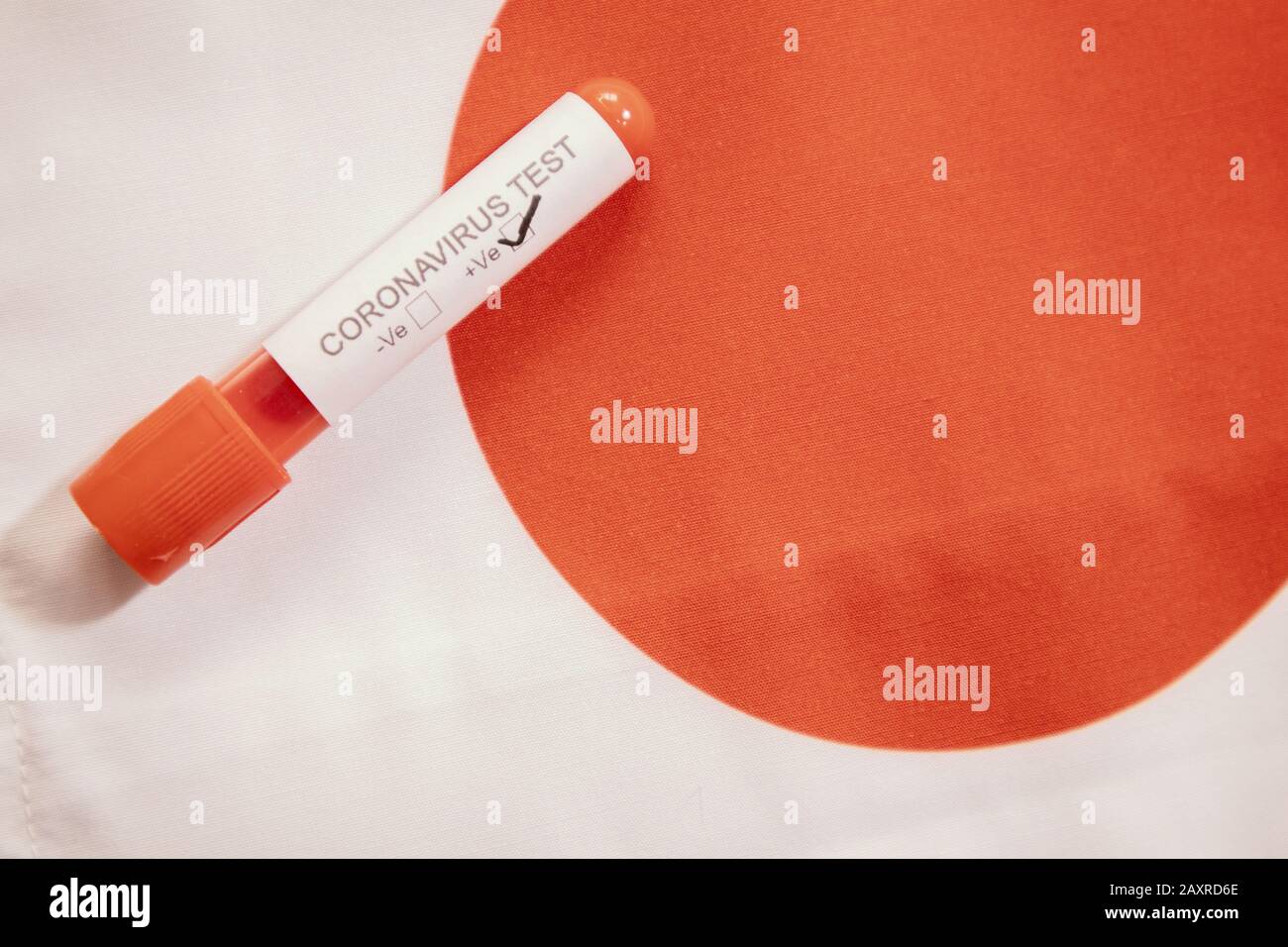Coronavirus positive test on blood collection tubes on Japan flag - concept of virus found in Japan. Stock Photo