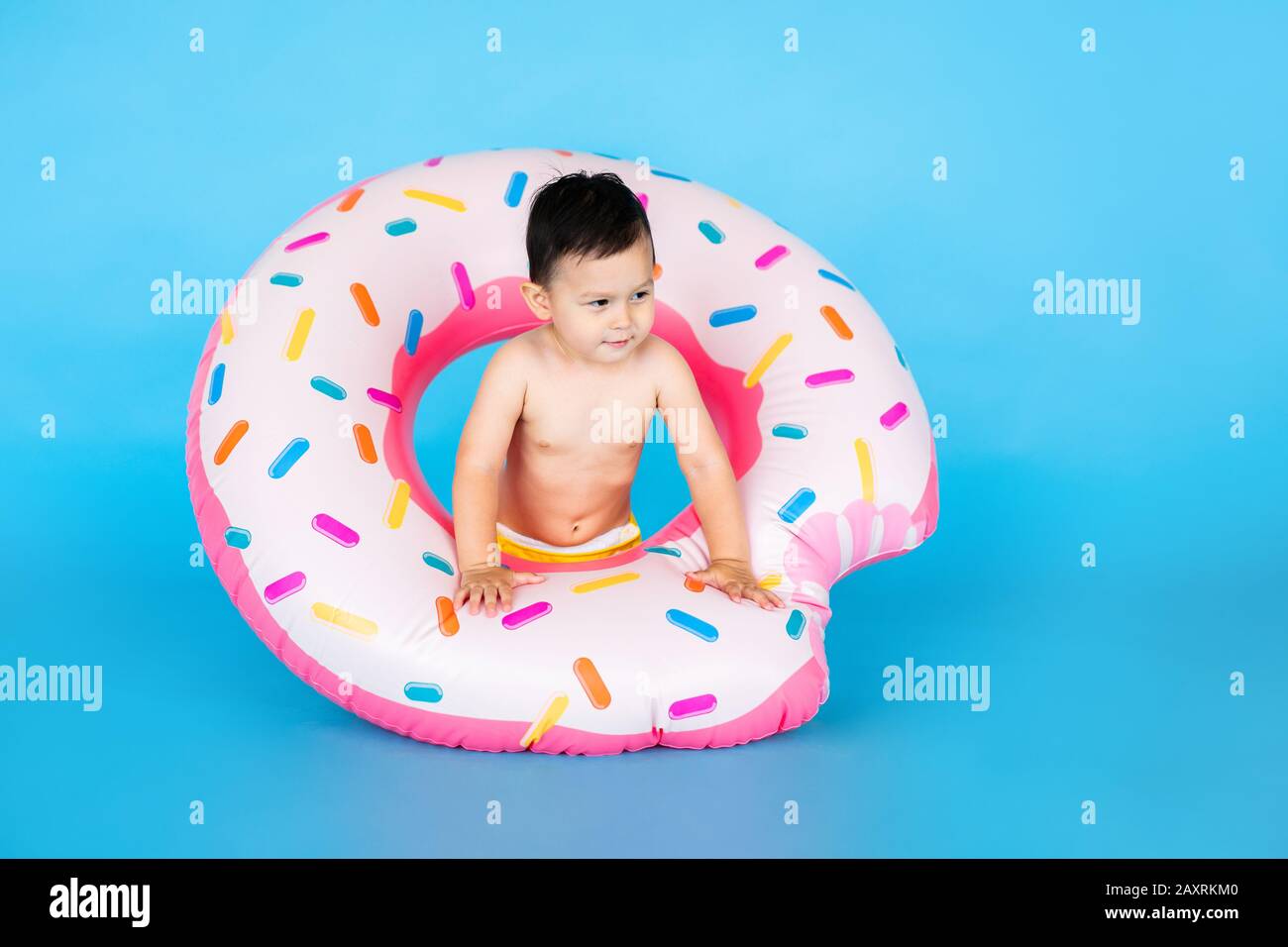 Happy Baby Boy In Swimsuit With Swimming Ring Donut On A Colored