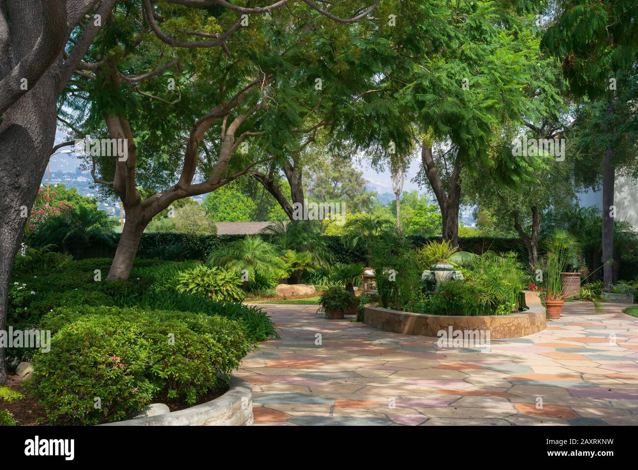 California courtyard with stone patio, lush plants, and a cozy canopy created by a healthy amount of trees Stock Photo