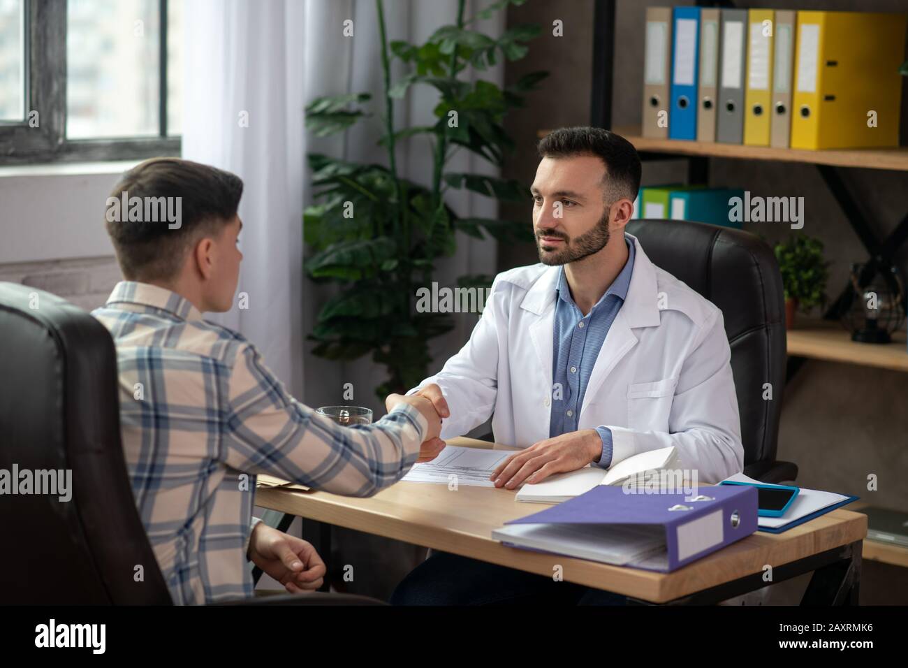 Dark-haired young doctor explaining the case to the patient Stock Photo