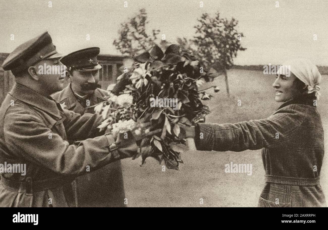Red Army in 1930s. From soviet propaganda book of 1937. An  ordinary Soviet woman gives a bouquet of flowers to marshals Voroshilov and Marshal Budyon Stock Photo