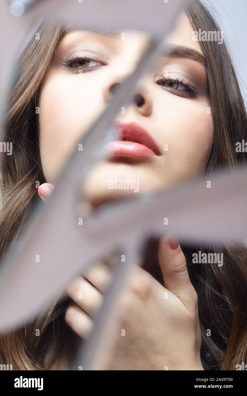 Young woman looks in a broken mirror. Portrait of beautiful female in