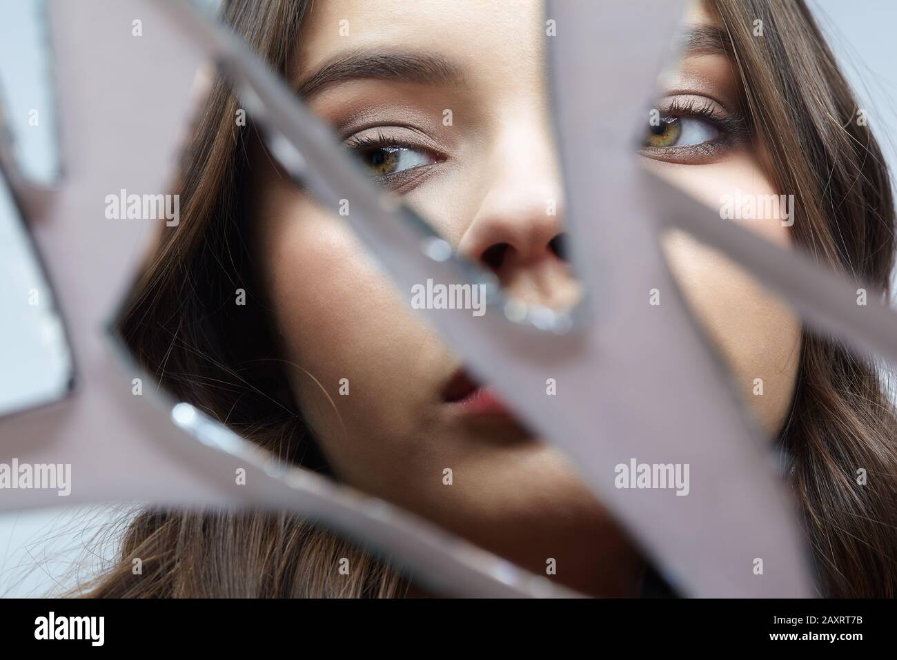 Young woman looks in a broken mirror. Portrait of beautiful female in