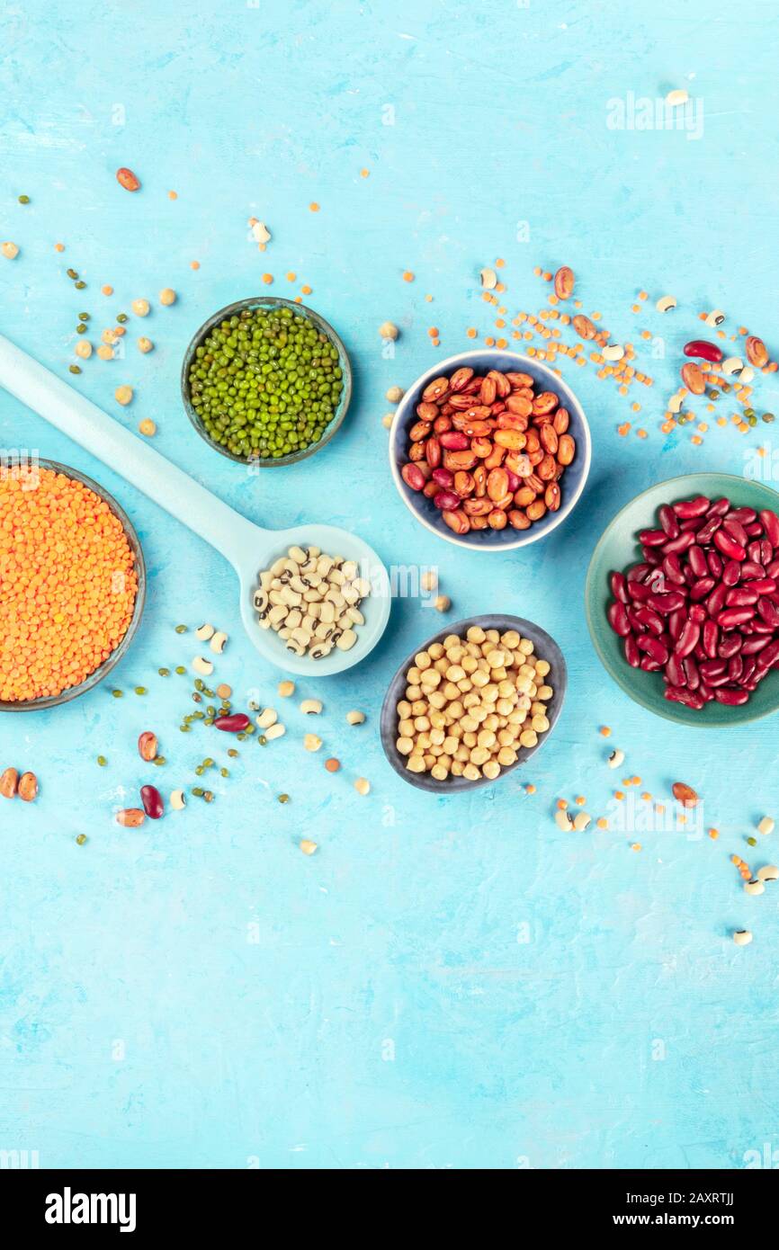 Various legumes flat lay. Different pulses, shot from above on a blue background with a place for text. Red beans, lentils, chickpeas, soybeans Stock Photo