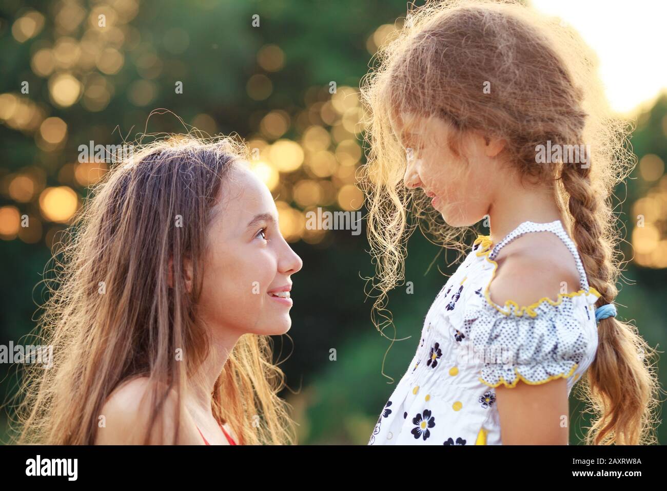 Two Cute little girls looking to each other and smiling at the  countryside. Happy kids spending time  outdoors Stock Photo