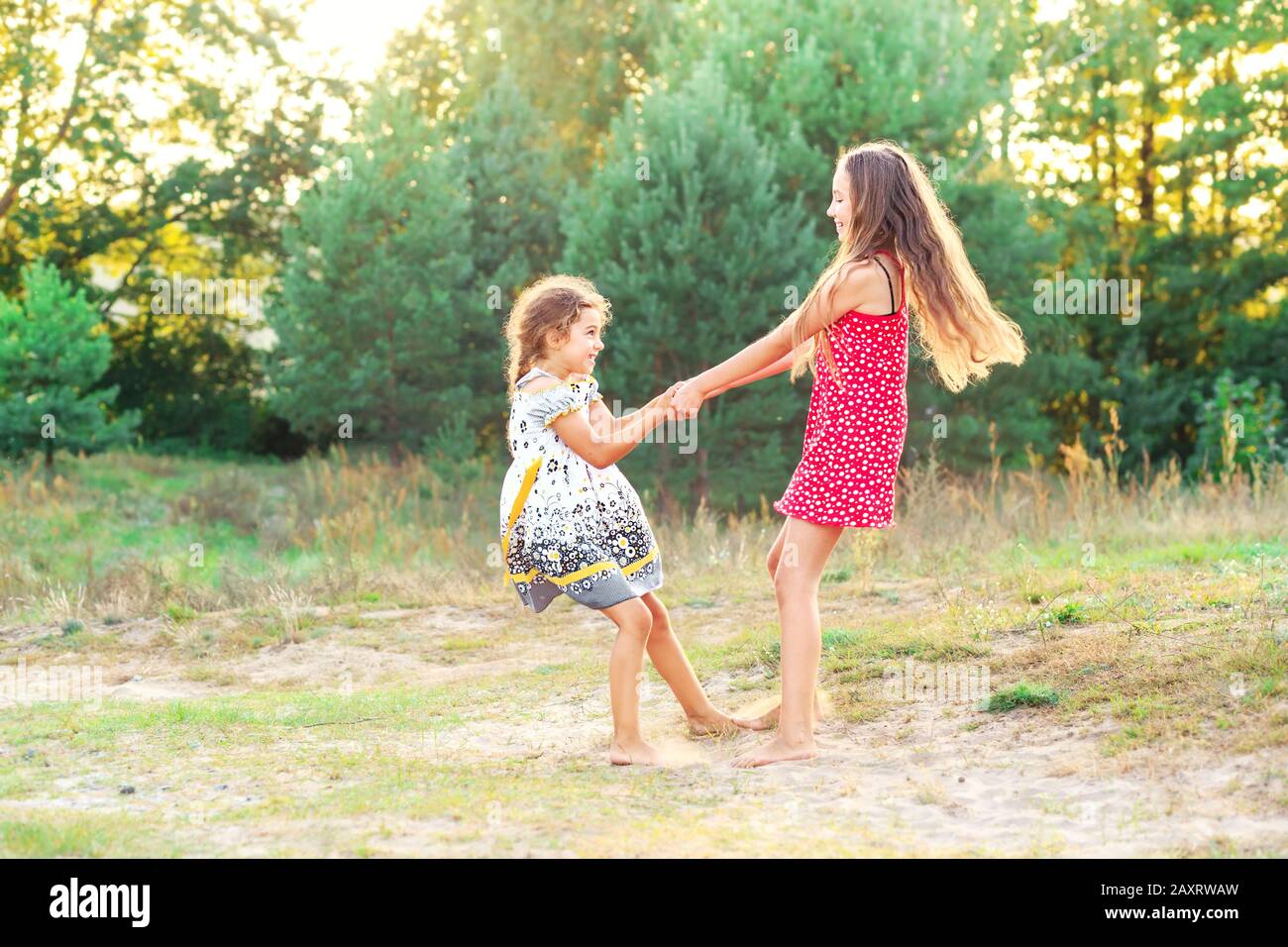 Two Happy cute little girls embracing and dancing at sunny summer day