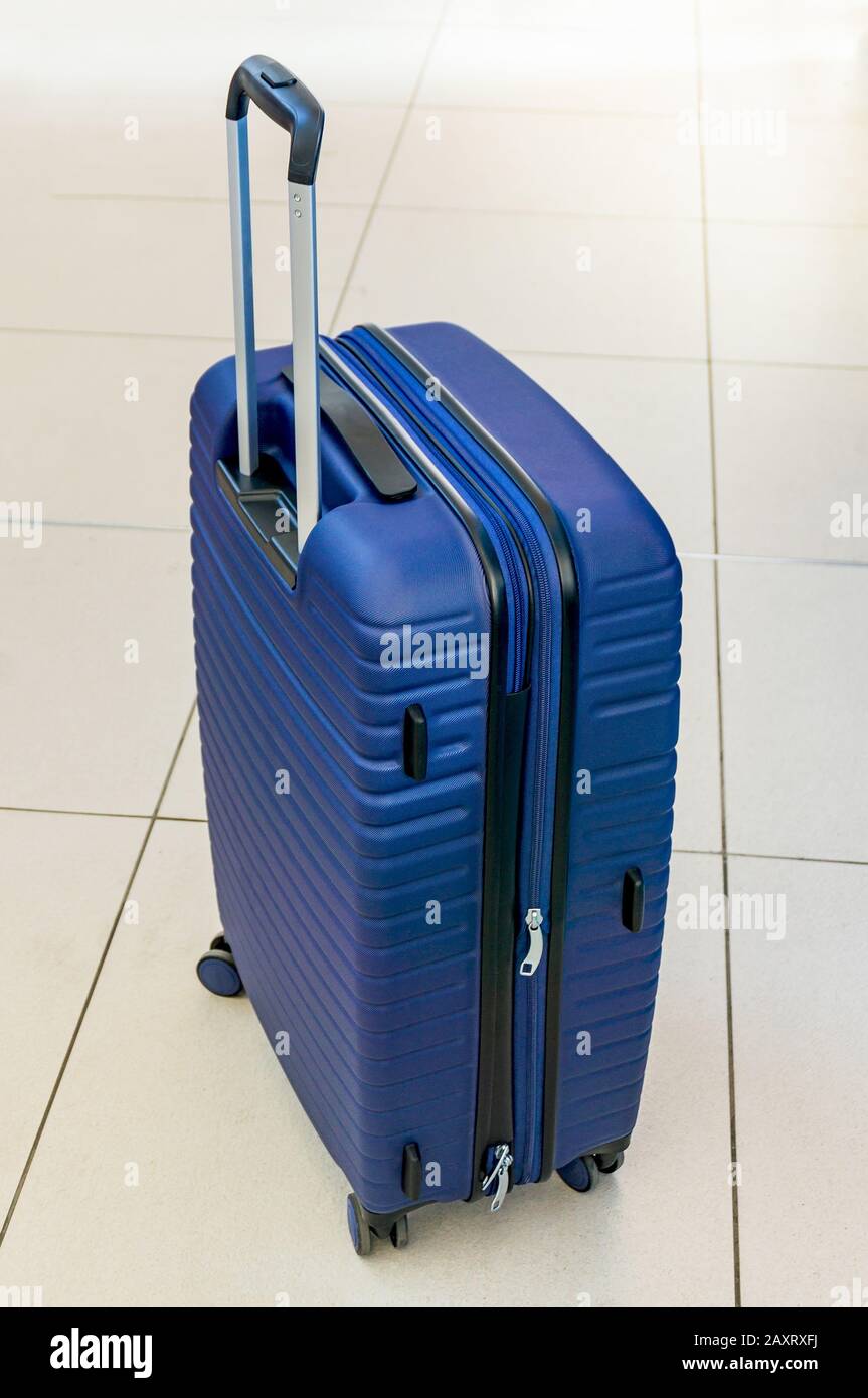 Blue suitcase on wheels. Baggage of a tourist. Waiting for travel by