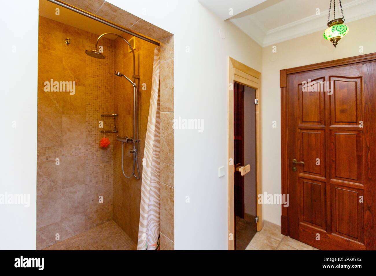 Shower in the sauna. Beige tiles. nice and cozy. The door to the steam room and the entrance door on the right. Stock Photo