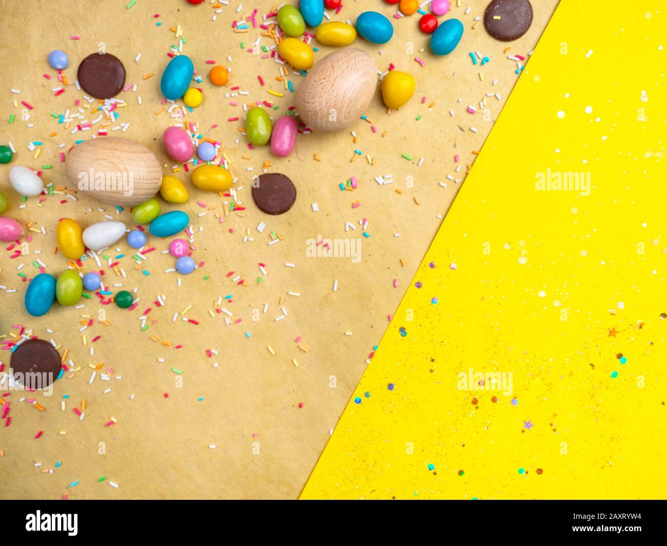 Colorful Easter eggs, sweets on yellow background, copy space Stock Photo