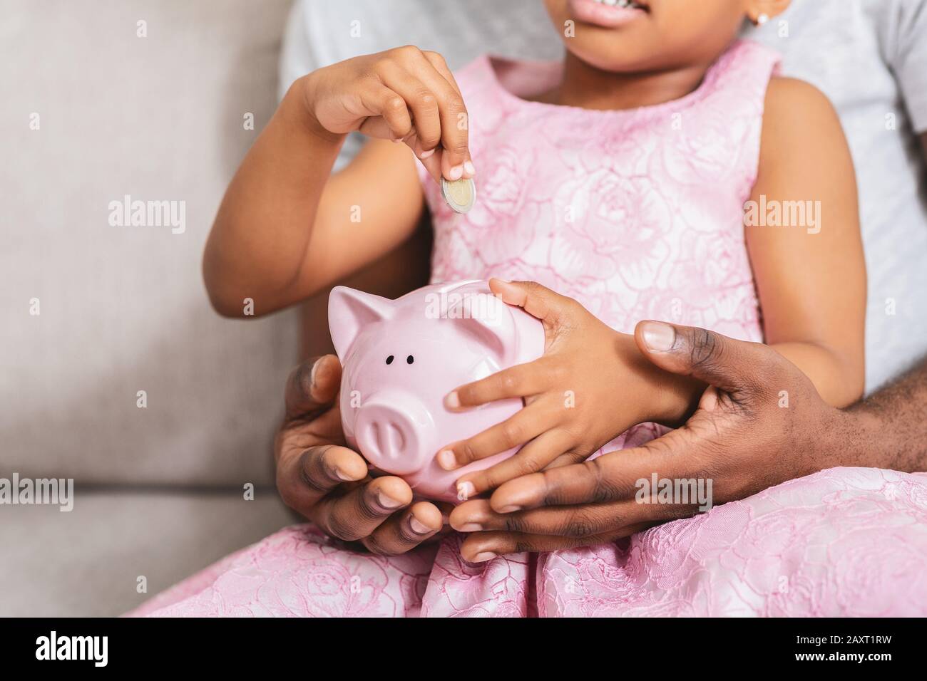 Cropped of little girl putting coins in piggy bank Stock Photo