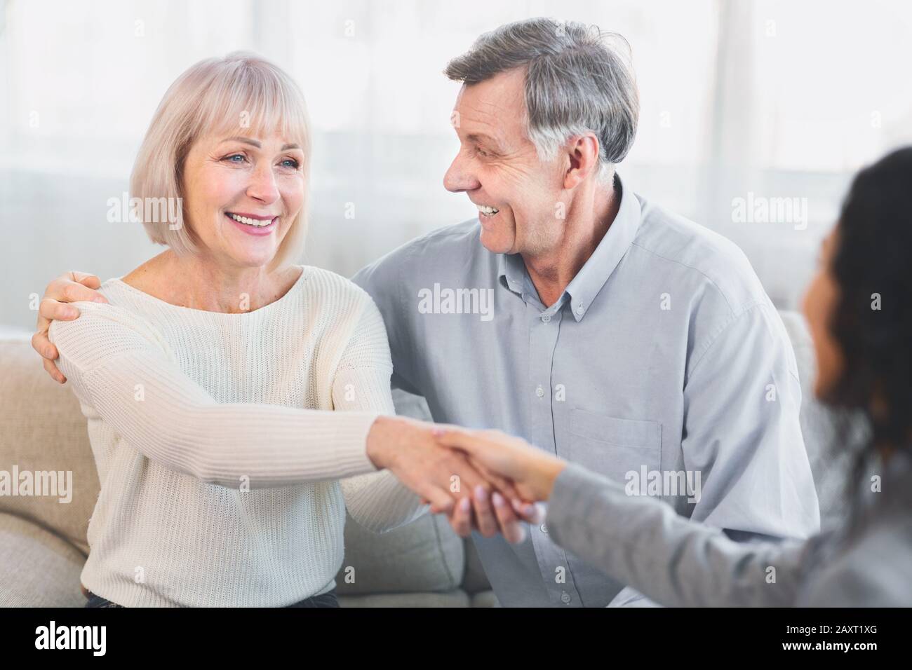 Happy elderly couple giving female doctor handshake Stock Photo