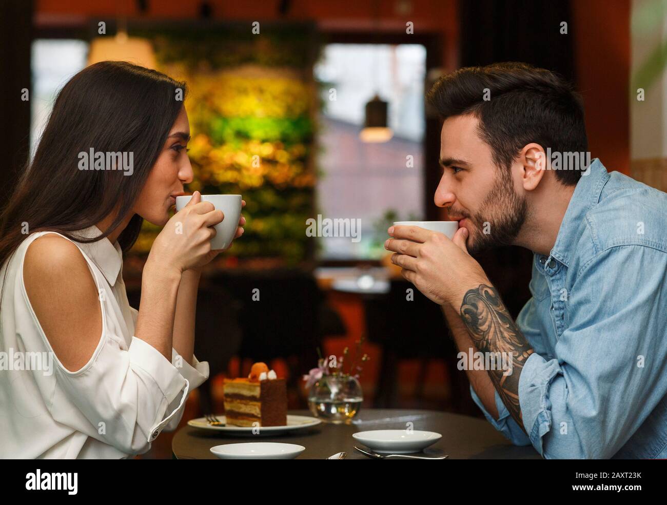 Couple Having Coffee Sitting In Cozy Cafe, Side View Stock Photo Alamy