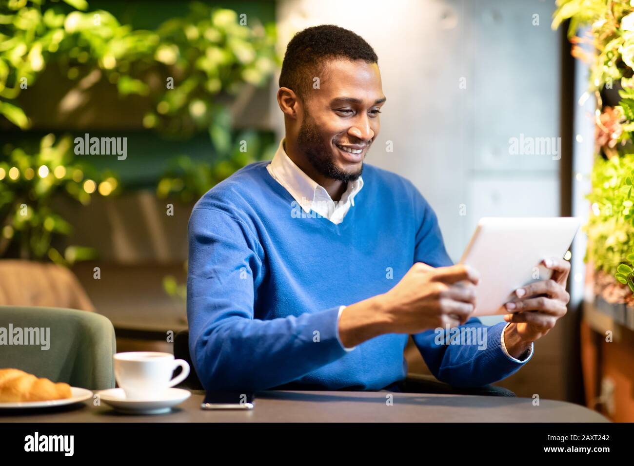 Black guy sitting in coffee shop working on his tablet Stock Photo - Alamy