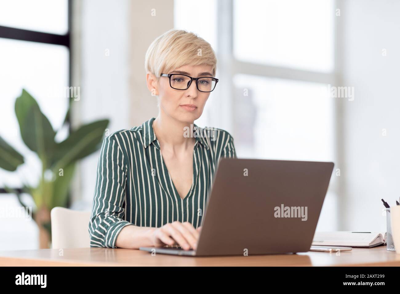 Serious Businesswoman Using Laptop Working In Modern Office Stock Photo