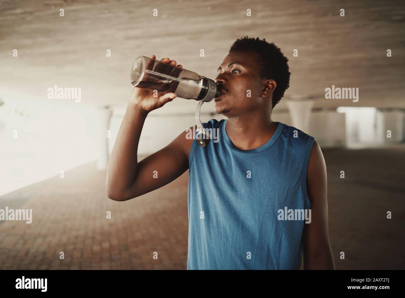 African american young man drinking water from bottle after jogging at outdoors Stock Photo