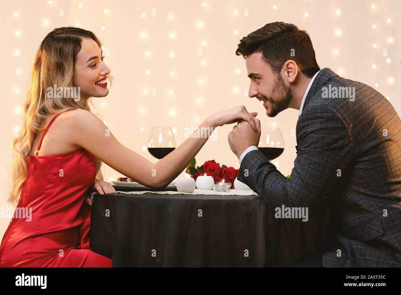 Gallant Man Kissing Girlfriend's Hand On Romantic Date In Restaurant Stock Photo