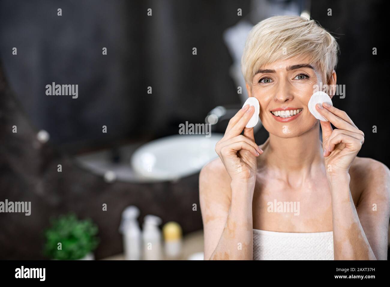 Lady Holding Cotton Pads Near Face Smiling Standing In Bathroom Stock Photo
