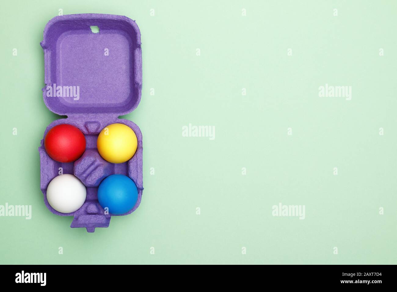 Box with colored easter eggs on a mint green background. Copy space. Stock Photo