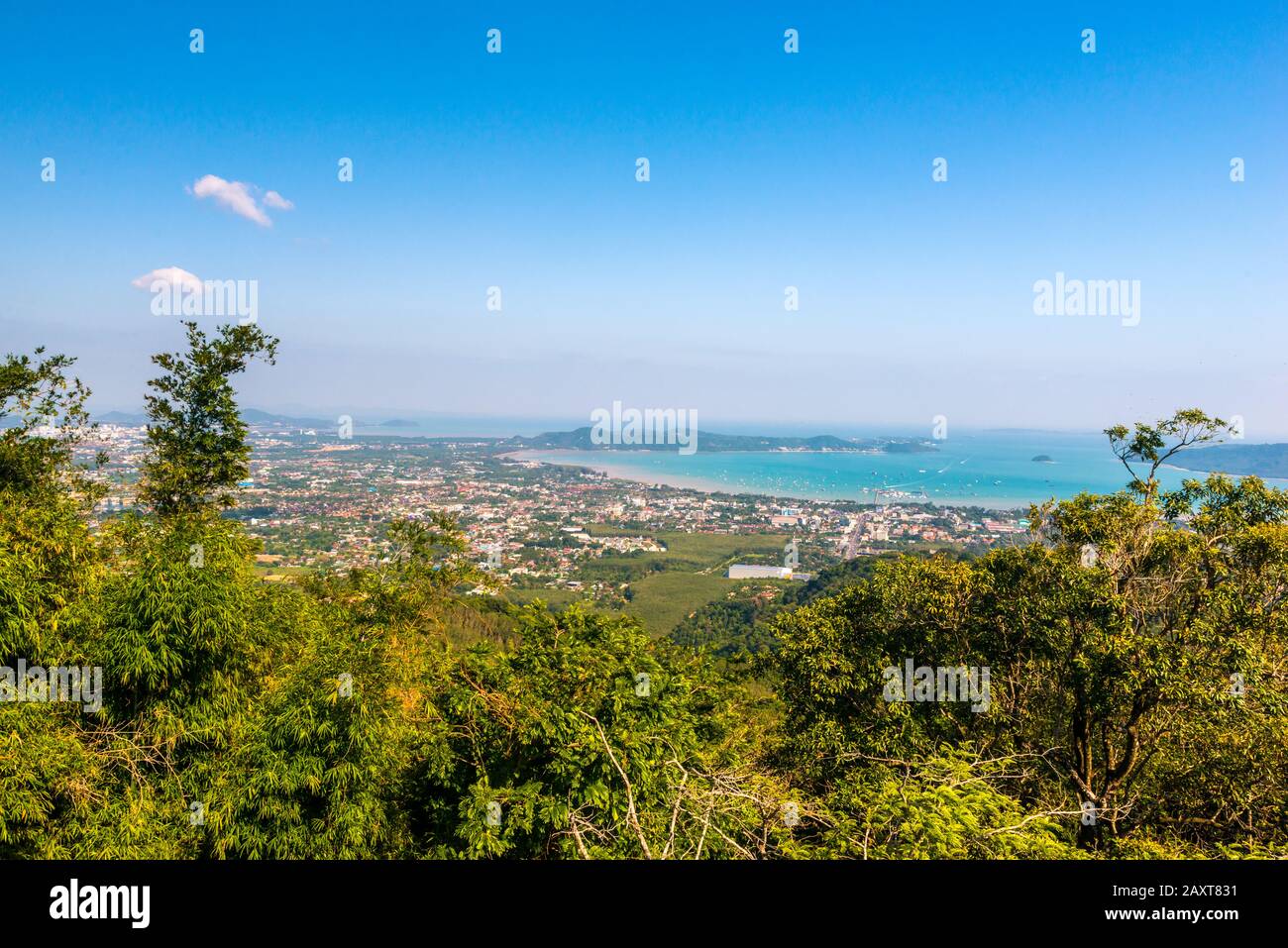 Nakkerd Hill, Phuket/Thailand-15December2019: Big Buddha hilltop viewpoint, trees in the foreground and the sea and cityscape in the background on a b Stock Photo