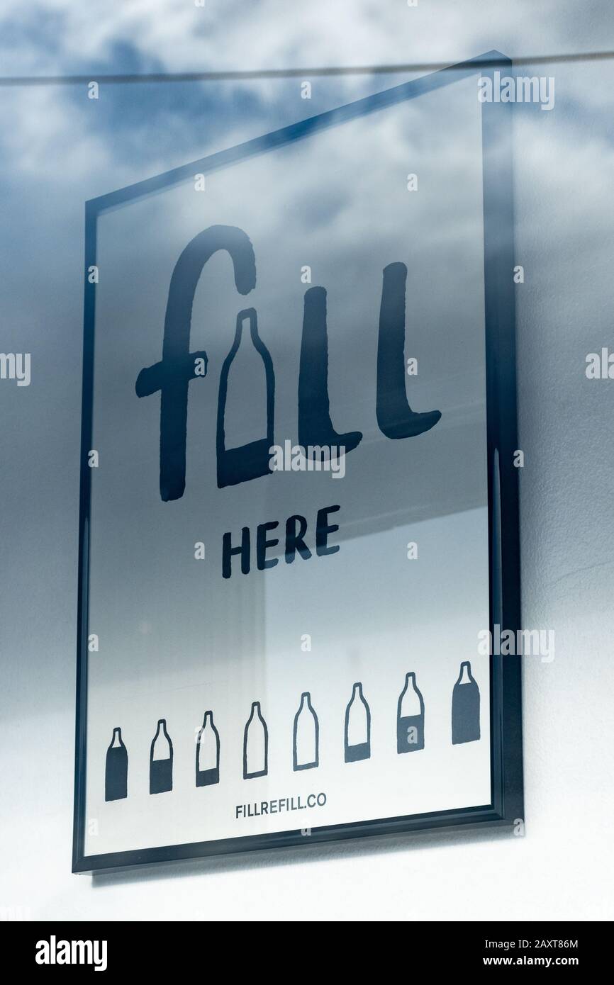 Zero waste shop selling sustainable and plastic-free goods, UK. Sign 'Fill here' in the shop window advertising refill facilities. Stock Photo