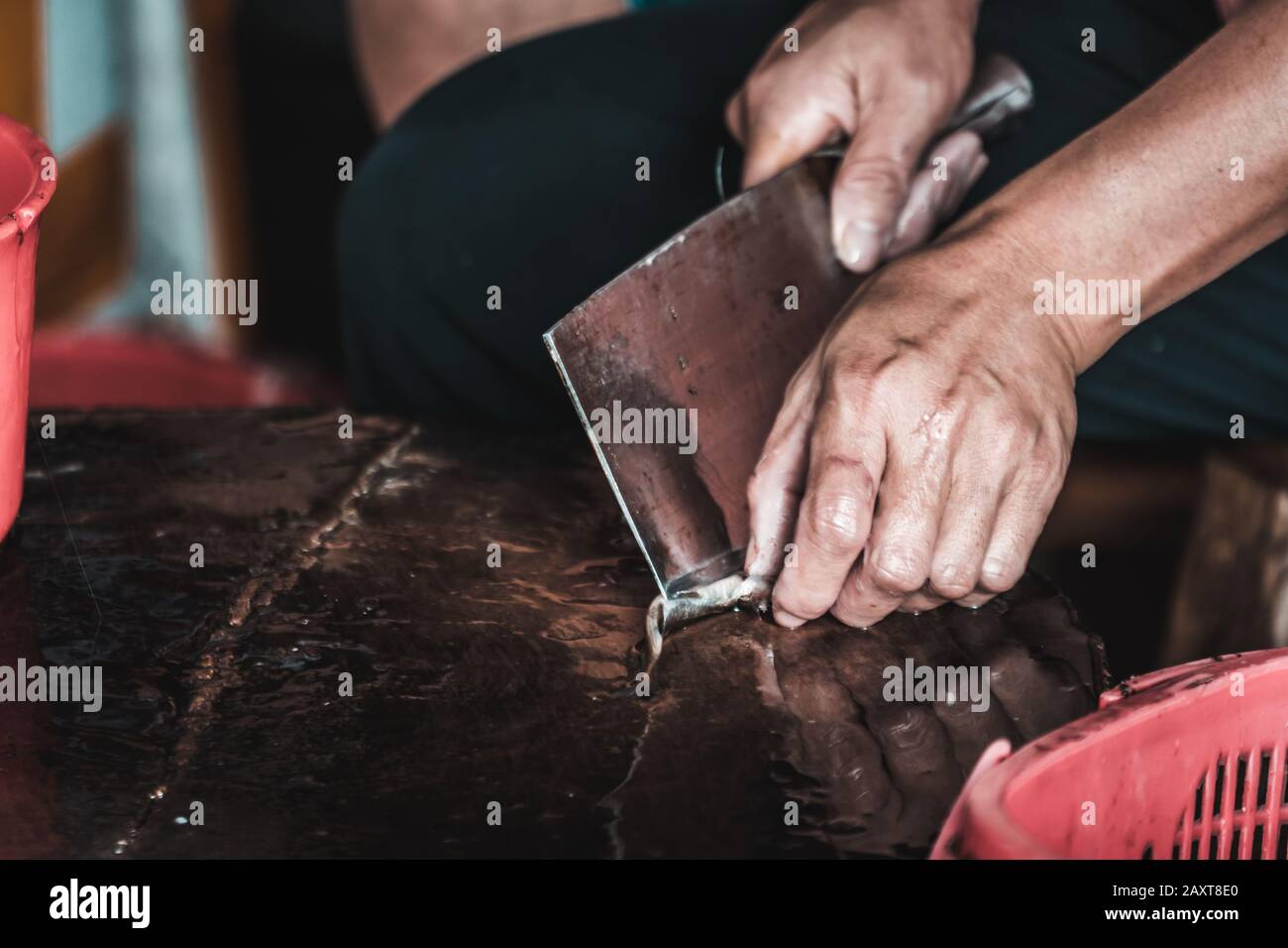 Close up of hands of a chinese person peeling scales off small fish on