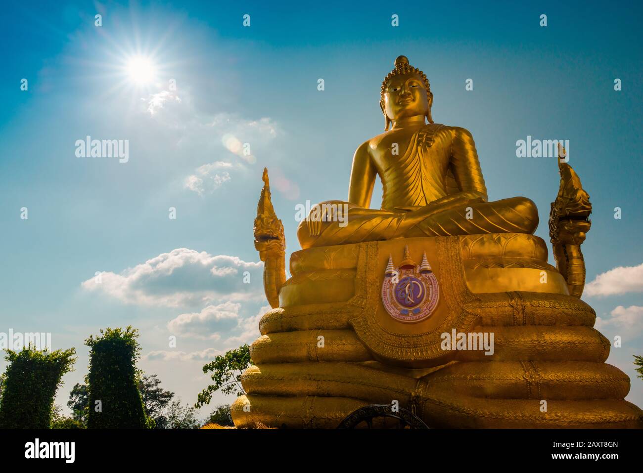 Nakkerd Hill, Phuket/Thailand-15December2019: Golden shining sitting buddha statue atop of the Big Buddha hill with a blue sky and clouds in backgroun Stock Photo