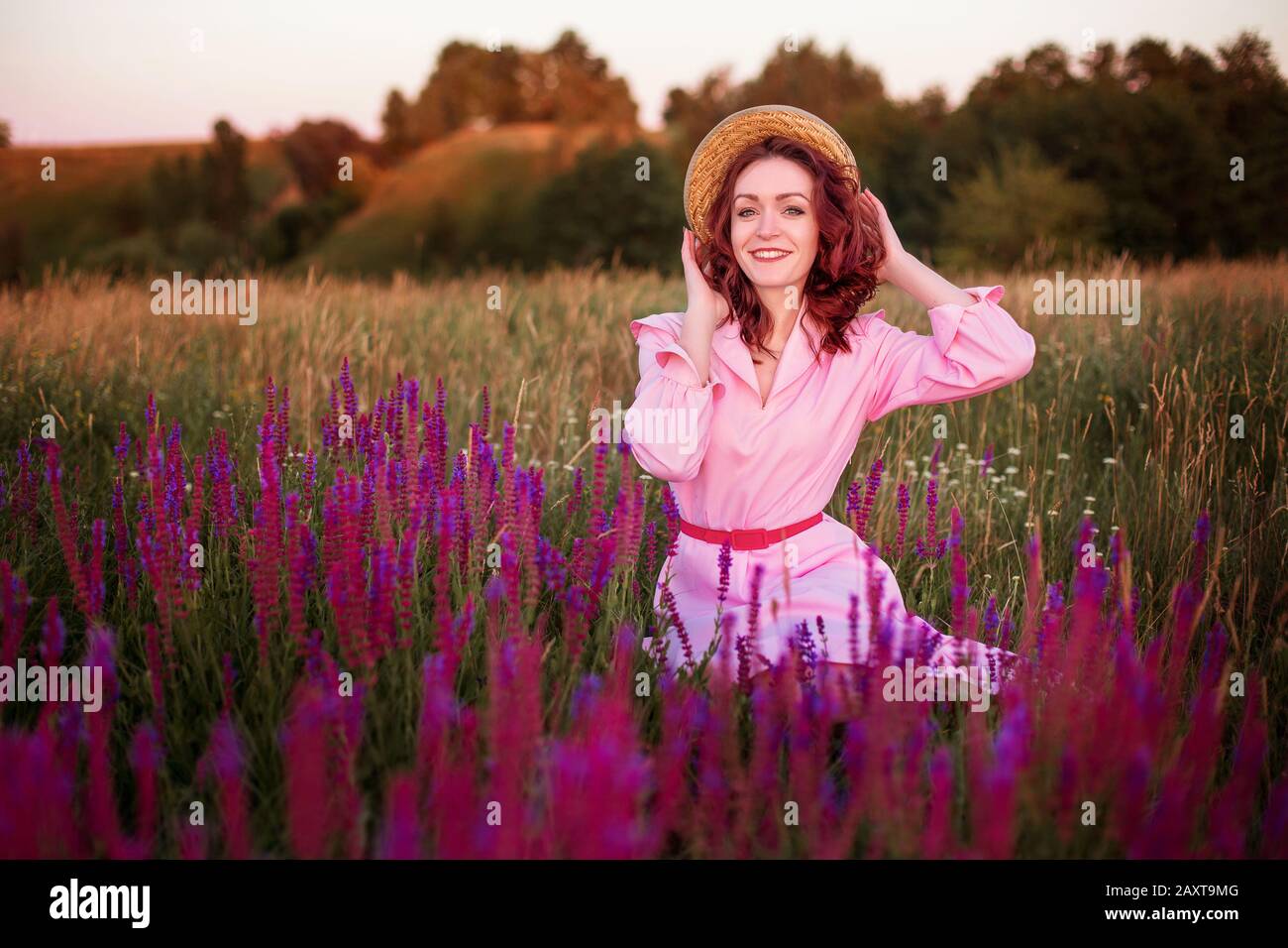 Beautiful young smiling woman in pink vintage dress and straw hat in ...