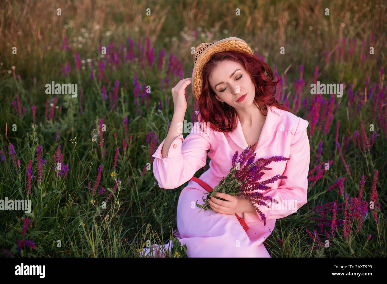 Beautiful young woman in pink vintage dress and straw hat in field ...