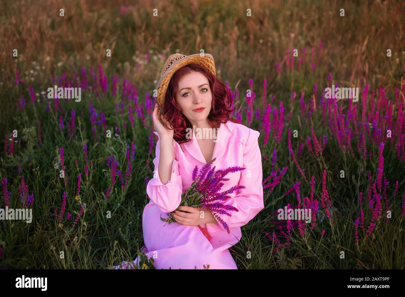 Beautiful young woman in pink vintage dress and straw hat in field ...