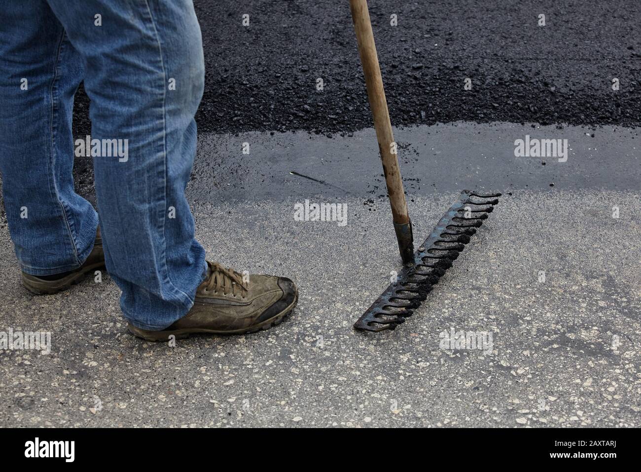 Workers using asphalt tools during road construction. Stock Photo