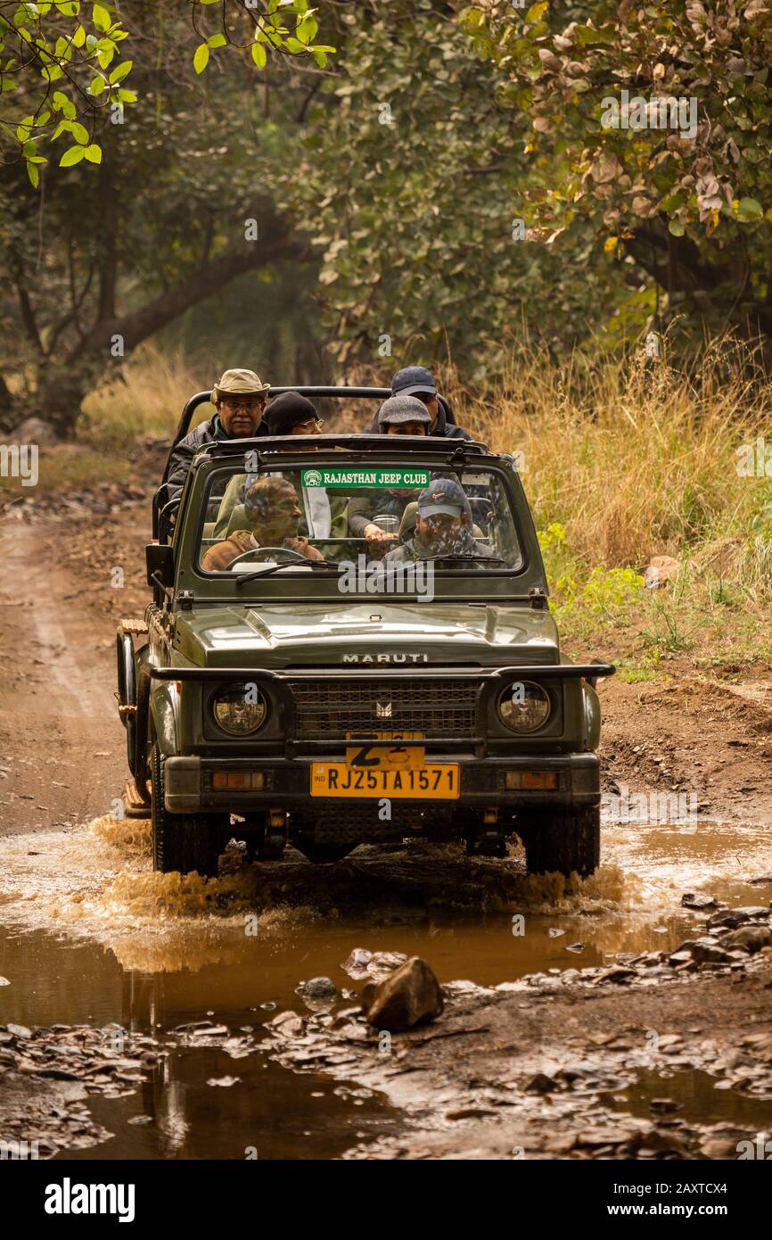 India, Rajasthan, Ranthambhore, National Park, Zone 2, Maruti Suzuki gypsy jeep carrying rich Indian tourists on afternoon safari driving through stre Stock Photo