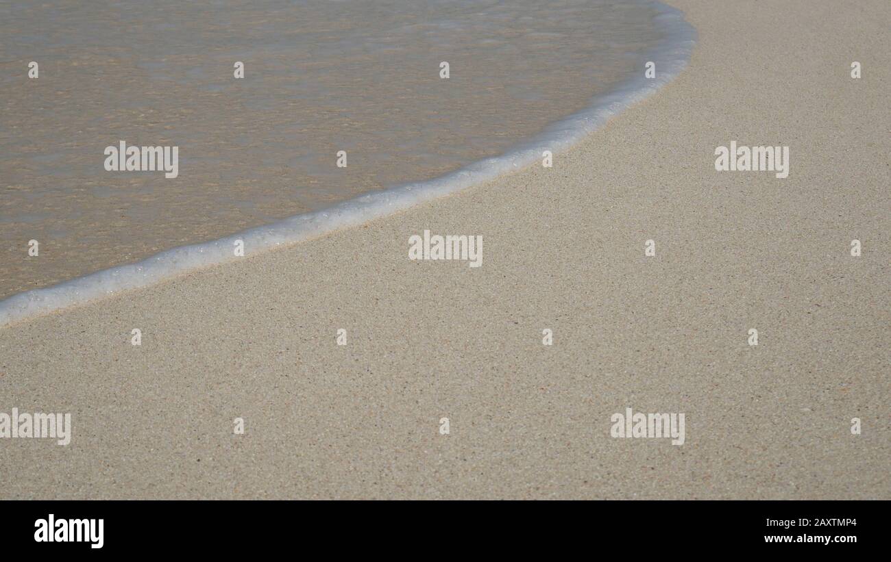 soft wave with bubble of blue ocean on white sand at tropical beach on summer season. simple beach background for summer holiday Stock Photo