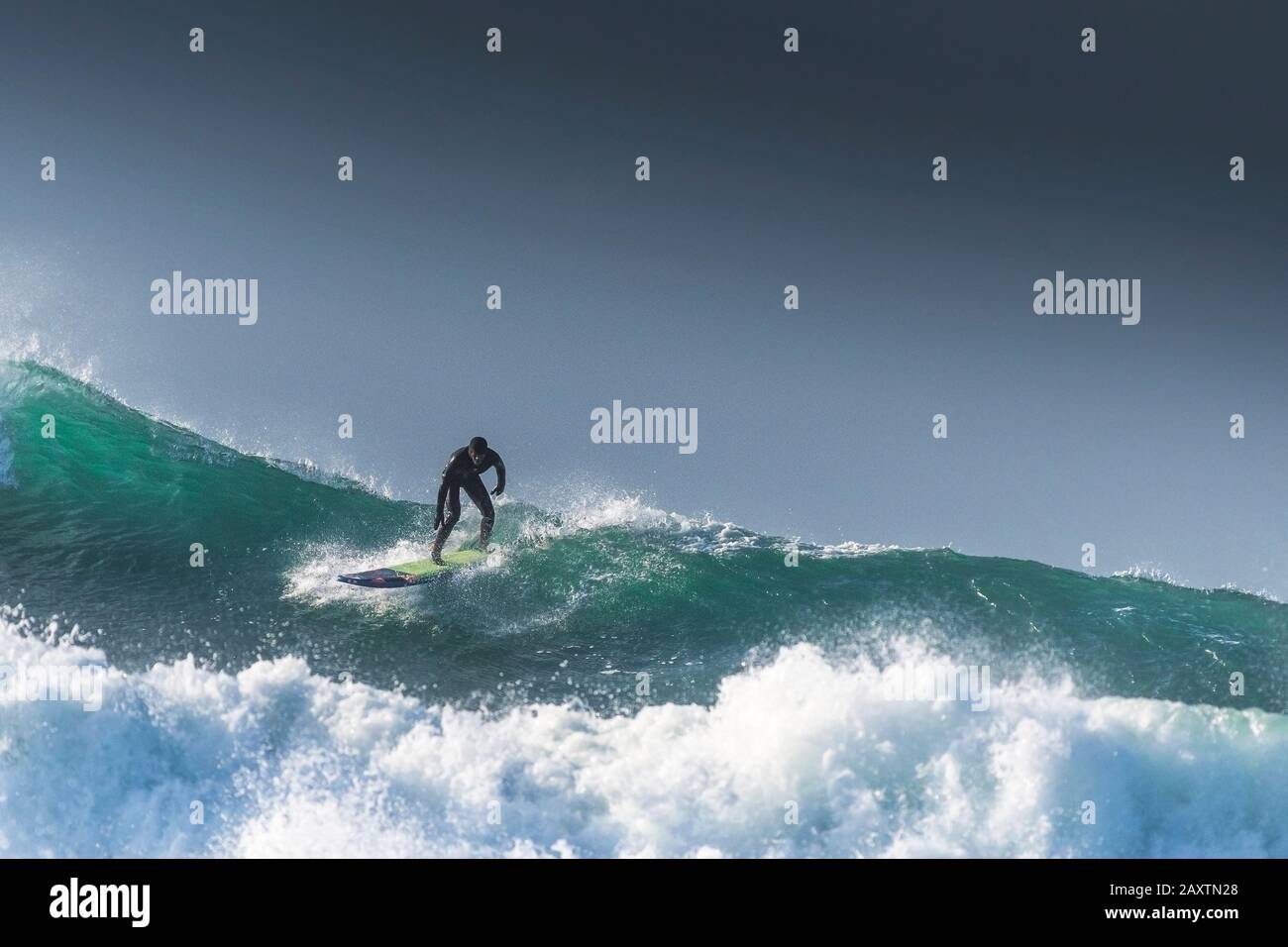 A surfer riding on the crest of a huge towering wave at Fistral in ...