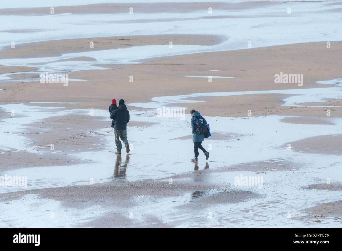 A family walking at low tide across Fistral Beach in Newquay in