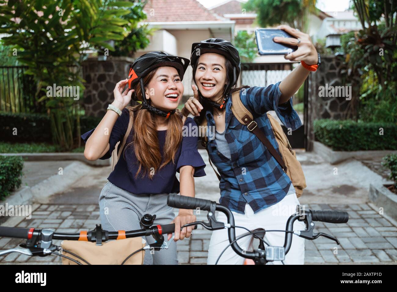 Two asian young woman wearing helmet and bags with camera cellphone make a video content on folding bike before go to campus Stock Photo