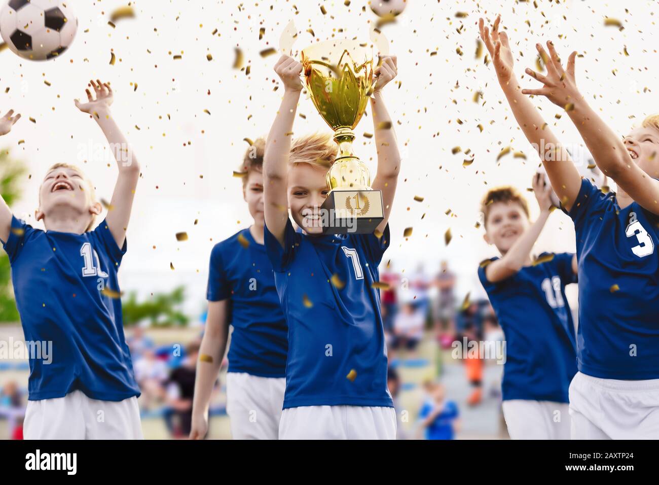 Champion youth soccer team with winning trophy. Boys football team celebrating victory in school competition by rising up golden cup. Happy kids as so Stock Photo