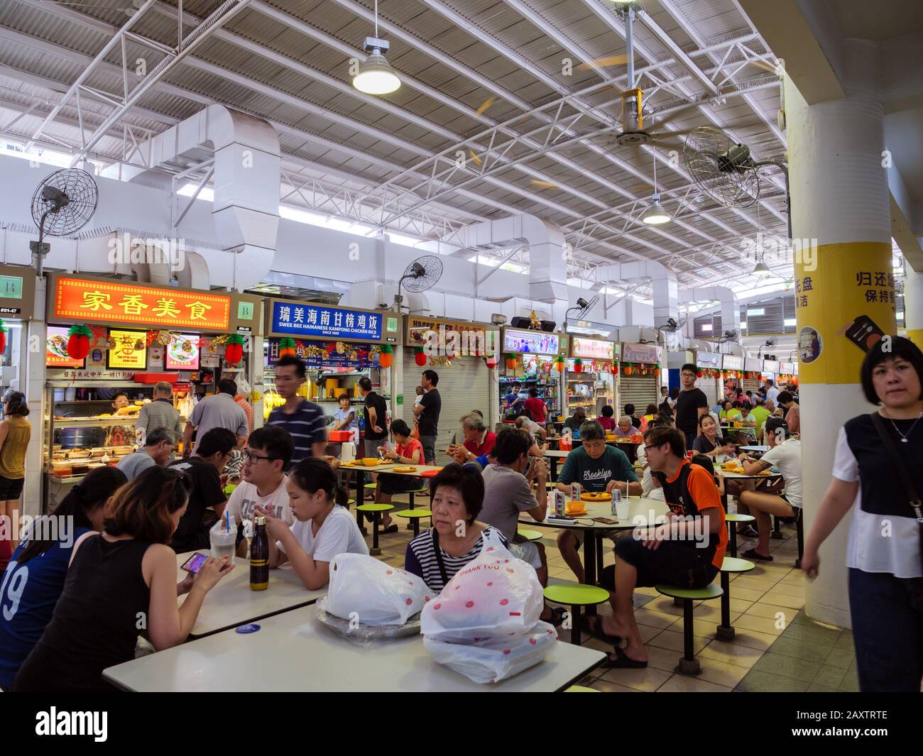 SINGAPORE – 4 JAN 2020 – Asian Chinese diners having a meal and socialising at a crowded self-service hawker centre in Ang Mo Kio, Singapore, Southeas Stock Photo