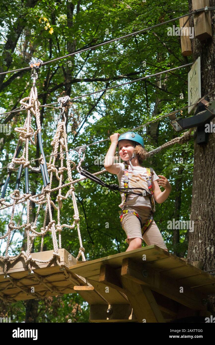 Young girl girls child kid on a children obstacle course activity Trail high in woodland forest tree, at an adventure park in France during the summer. (112) Stock Photo