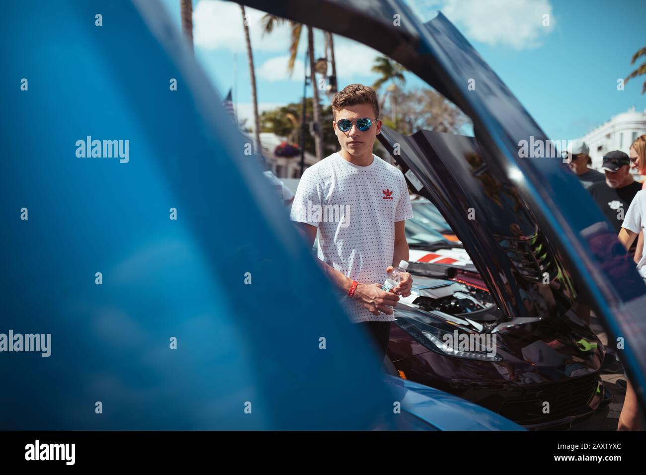Young rich boy with sunglasses with supercars in the sunny Naples, Florida Stock Photo