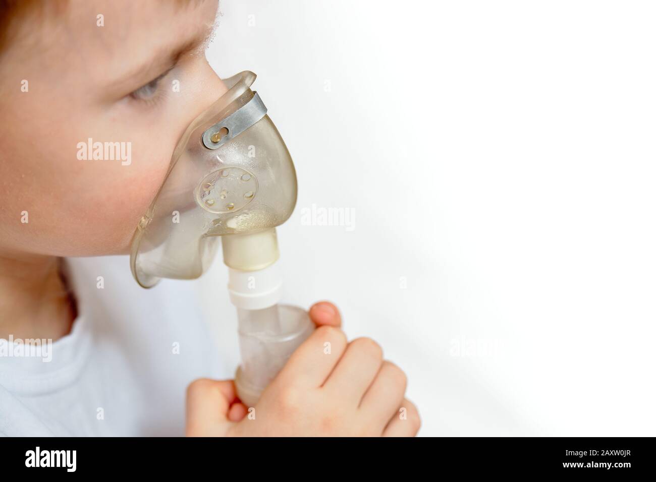 Child makes inhalation at home with nebulizer selective focuse on nebulaser mask with copy space. Example of combating respiratory diseases such as tr Stock Photo