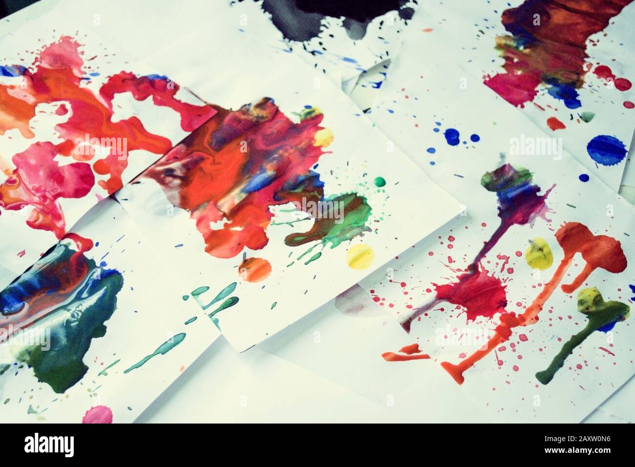 Many red colored blots on white paper with streaks. Abstract creative spots of paint on a white background. Red bright colors. Stained-spattered table Stock Photo