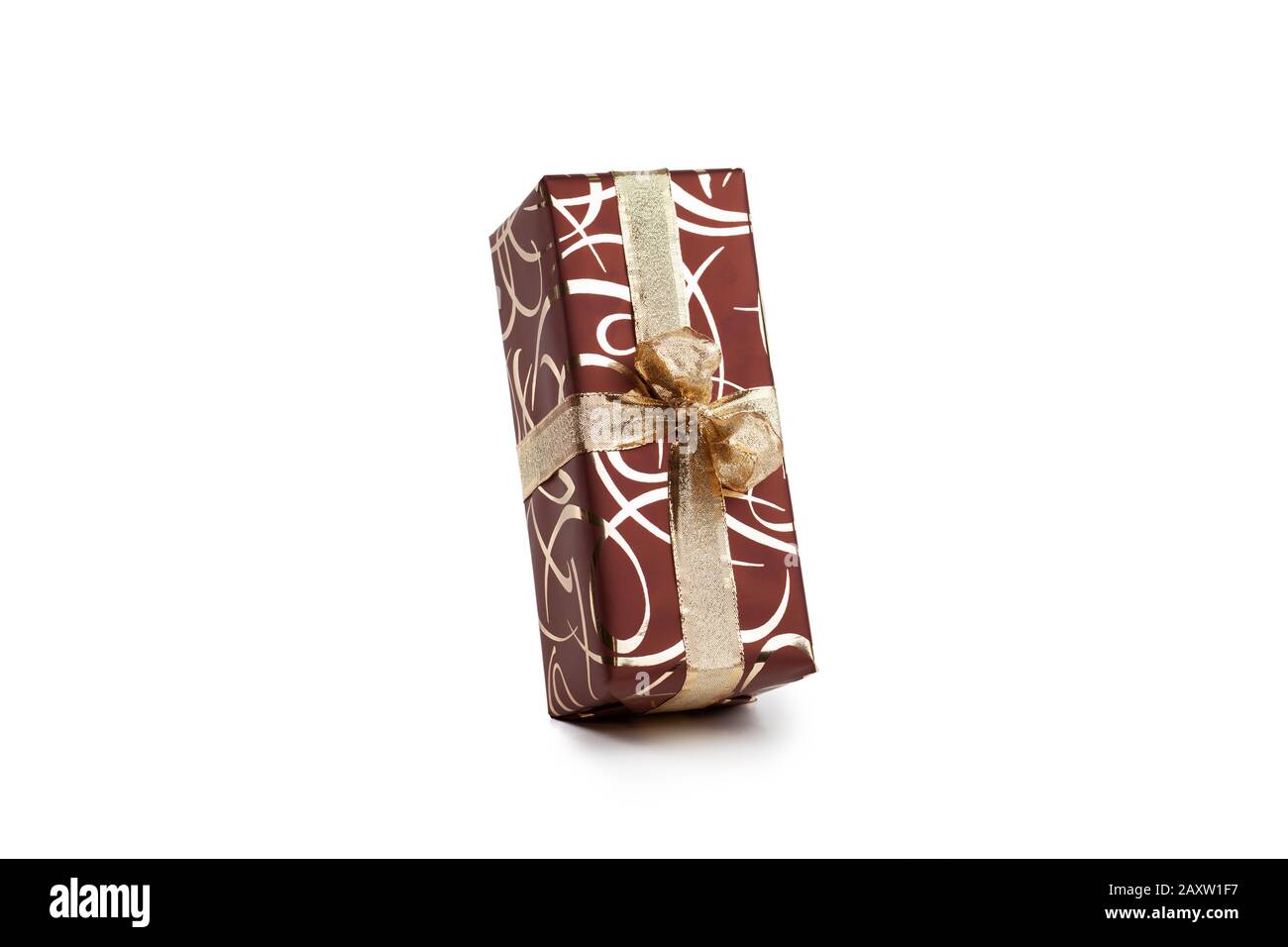 packaged rectangular gift in dark brown packaging with gold bow and gold pattern on a white background Stock Photo