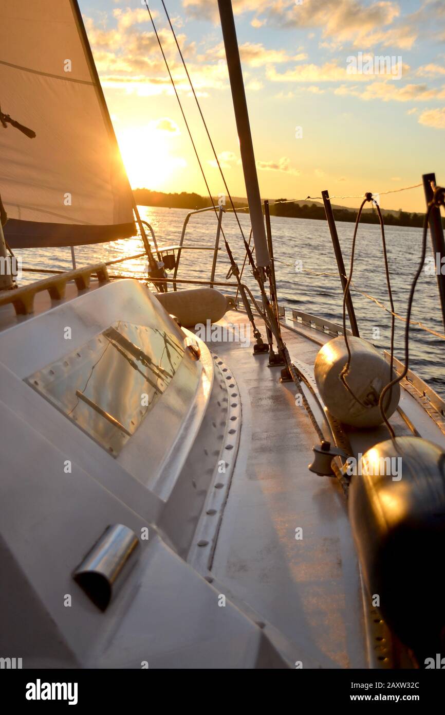 white sail yacht white against the blue sky with clouds and sun at
