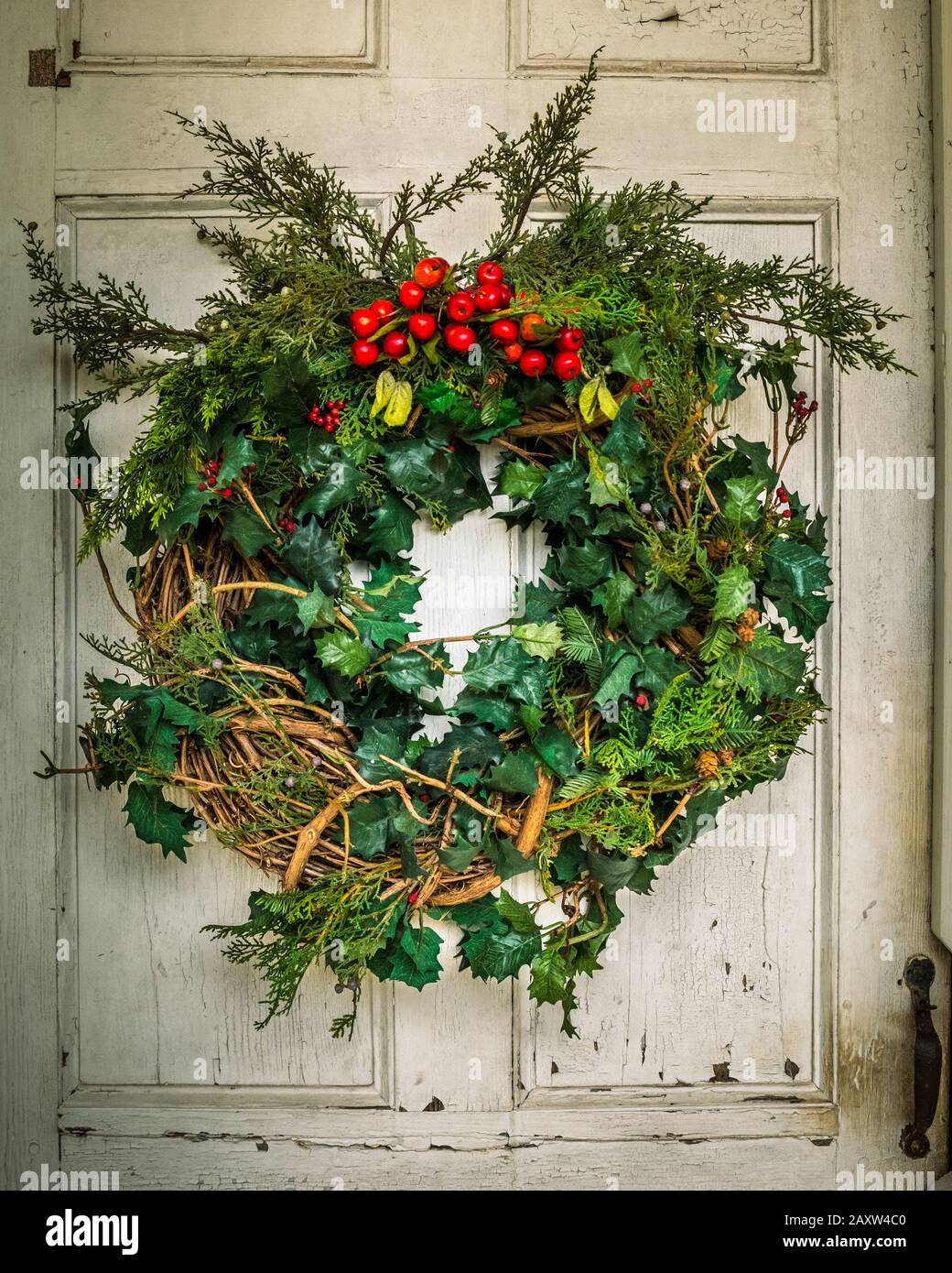 Handmade Christmas wreath hangs on rustic door. Stock Photo